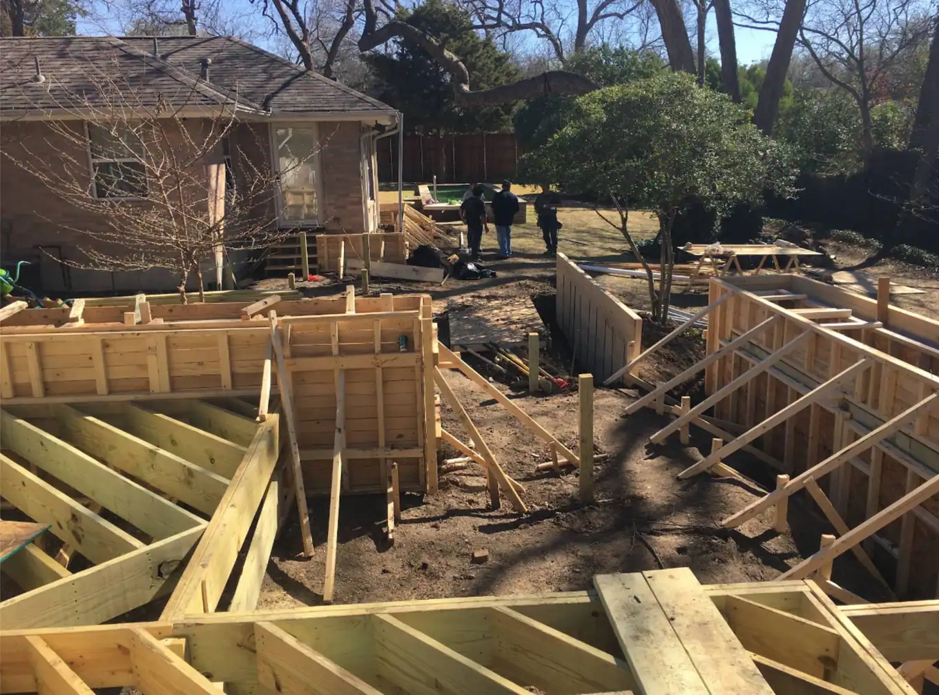 Deck framing and joists being built behind a house