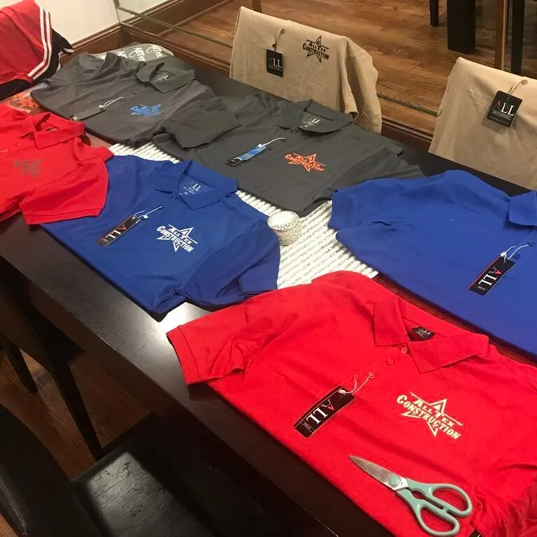 Stacks of red and blue AllTex logo shirts laid out on a table