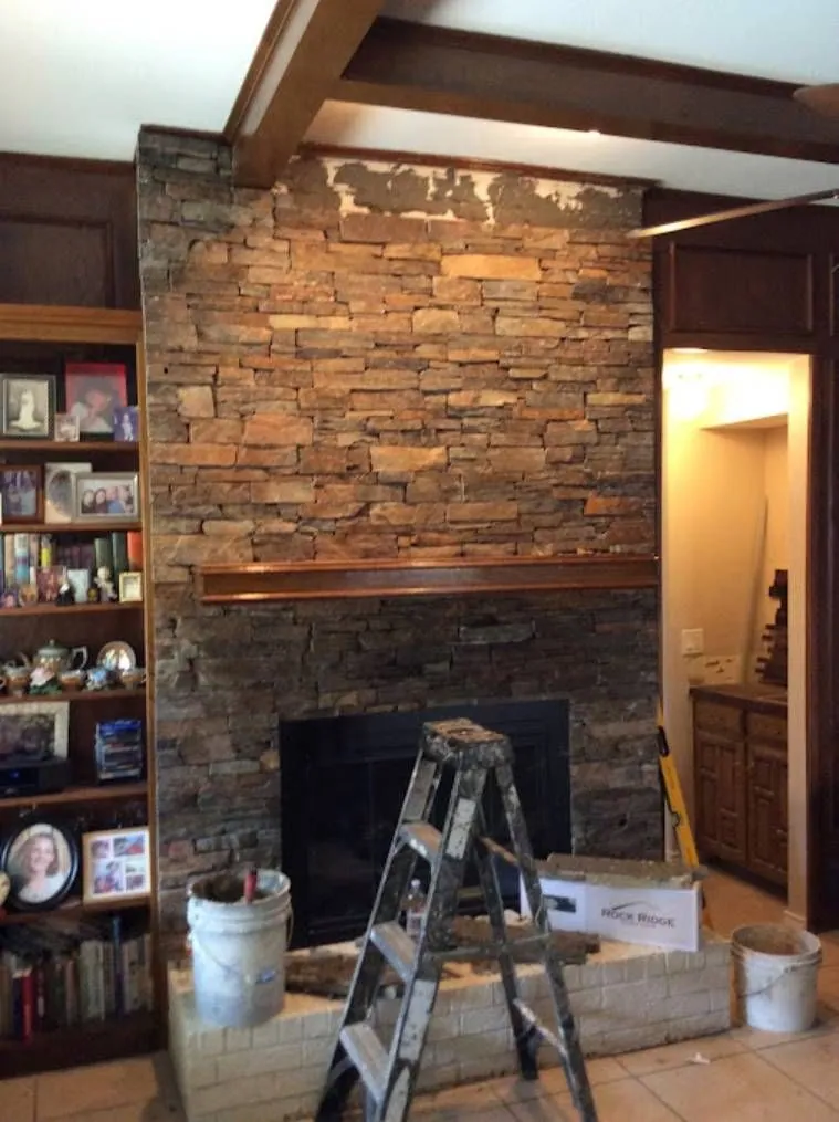 Living room with a stacked stone fireplace being finished