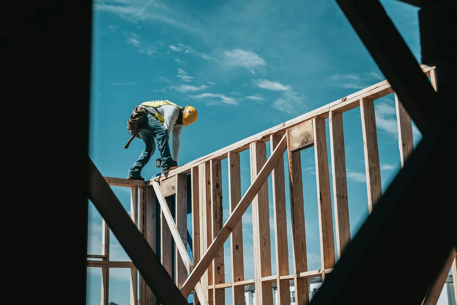 Framer in a hard hat working on the wood frame of a new house