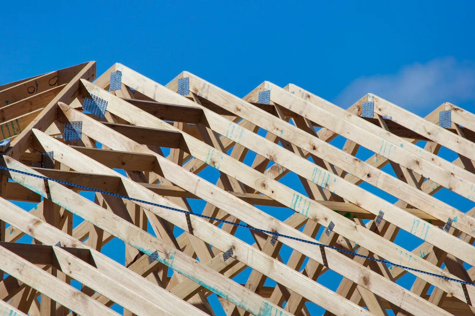 Timber wall framing and roof trusses of a new home against a blue sky