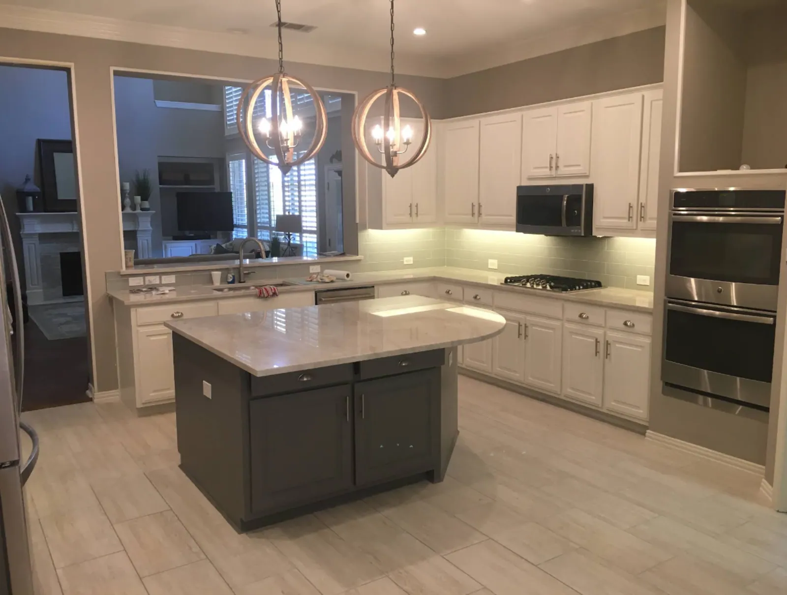 Remodeled kitchen with gray island and pendants