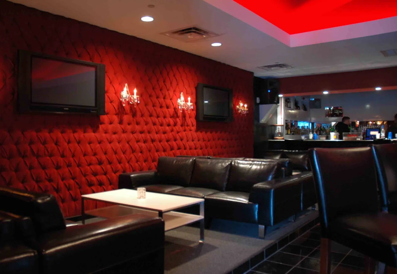 Lounge with a red tufted wall, leather sofas and wall sconces