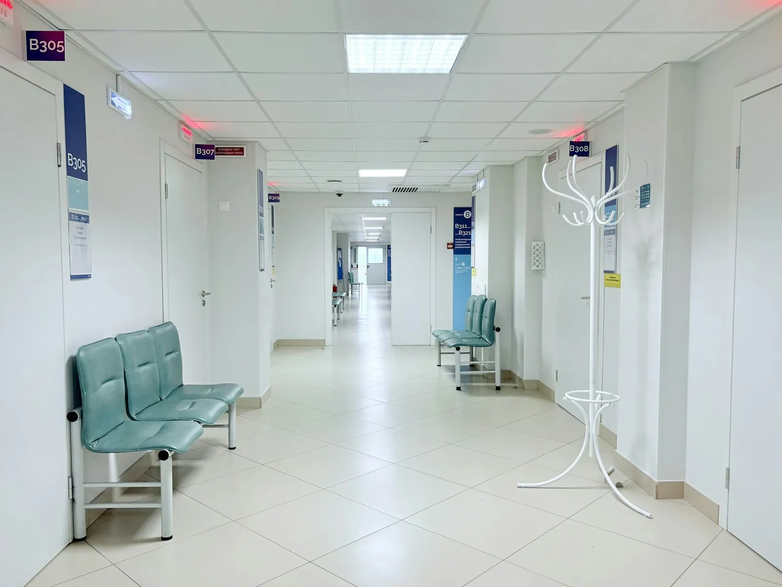 Bright clinic corridor with exam room doors and seating