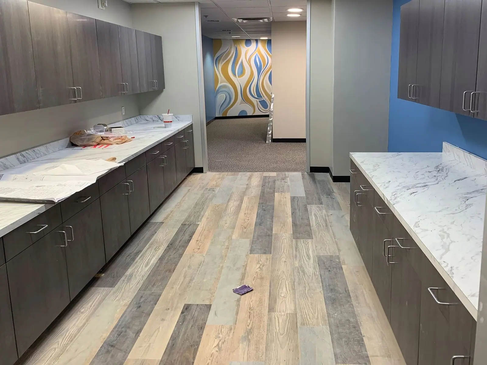 Finished office break room with long counters and wood-look plank floors