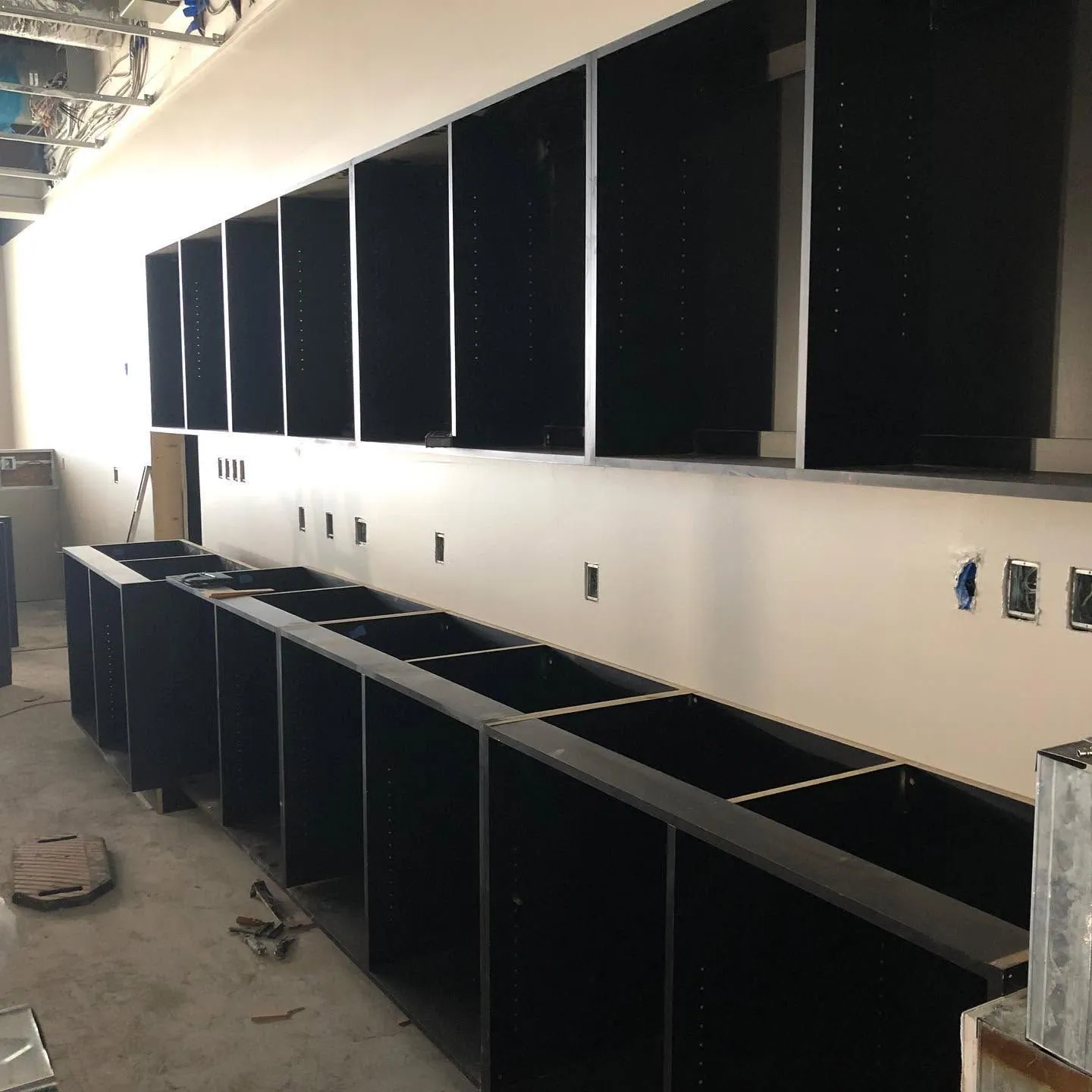 Dark casework cabinets being installed along a new office wall
