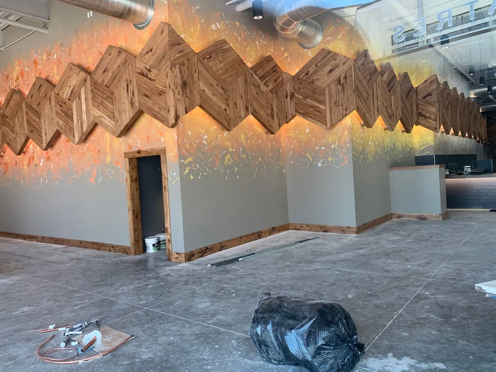 Restaurant dining room with a carved wooden chevron feature wall during finish out