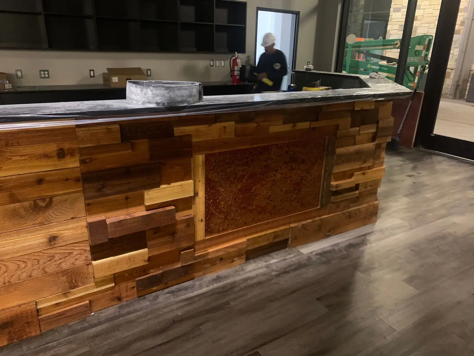 Bar front built from mixed reclaimed wood planks with a dark countertop