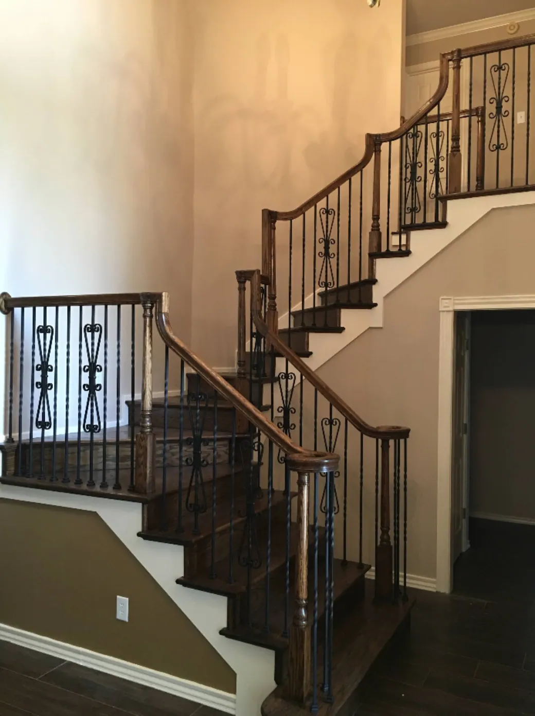 Curved staircase with iron balusters and dark wood treads
