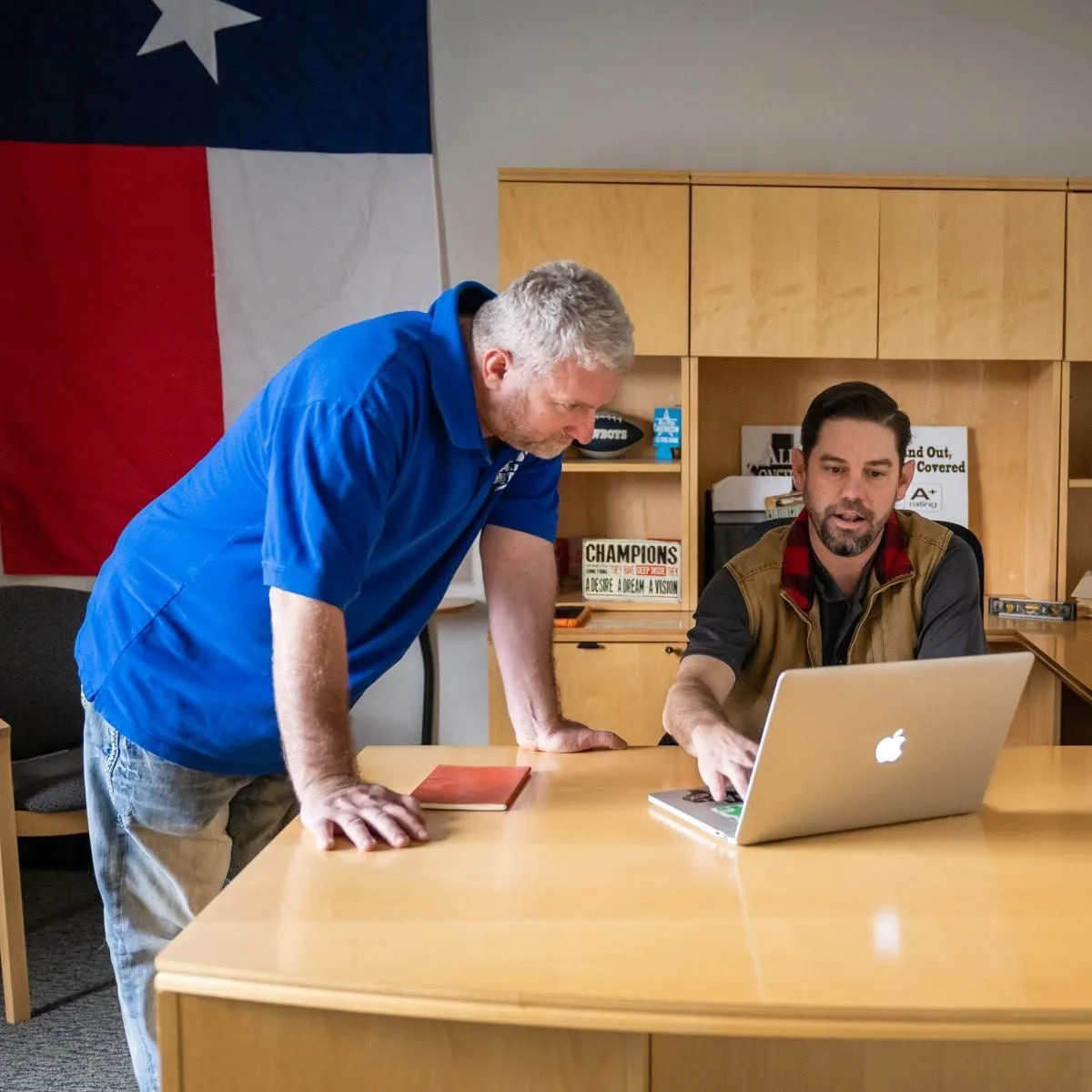 AllTex team members planning a project at a desk under a Texas flag