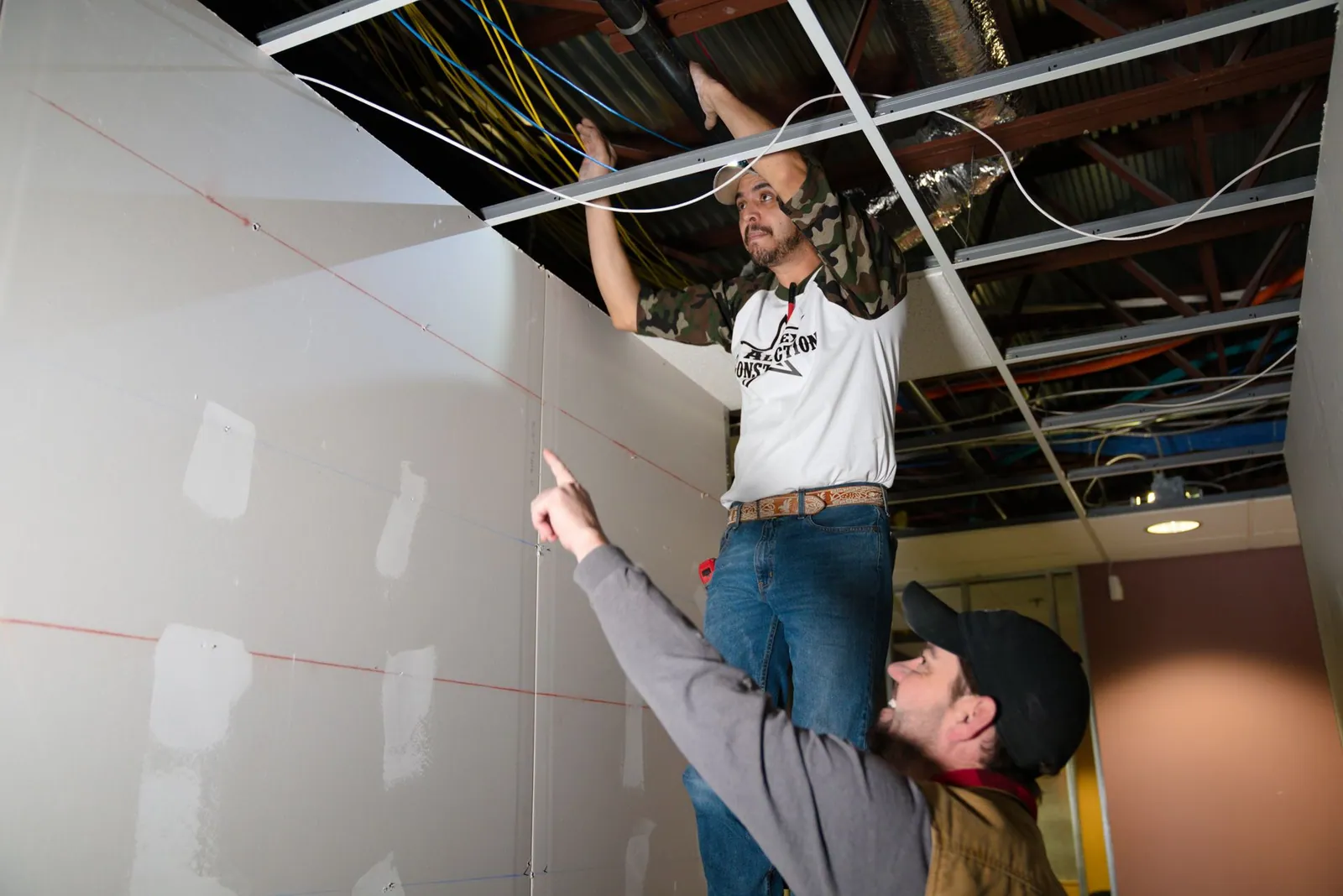 AllTex crew hanging drywall beneath an open ceiling grid
