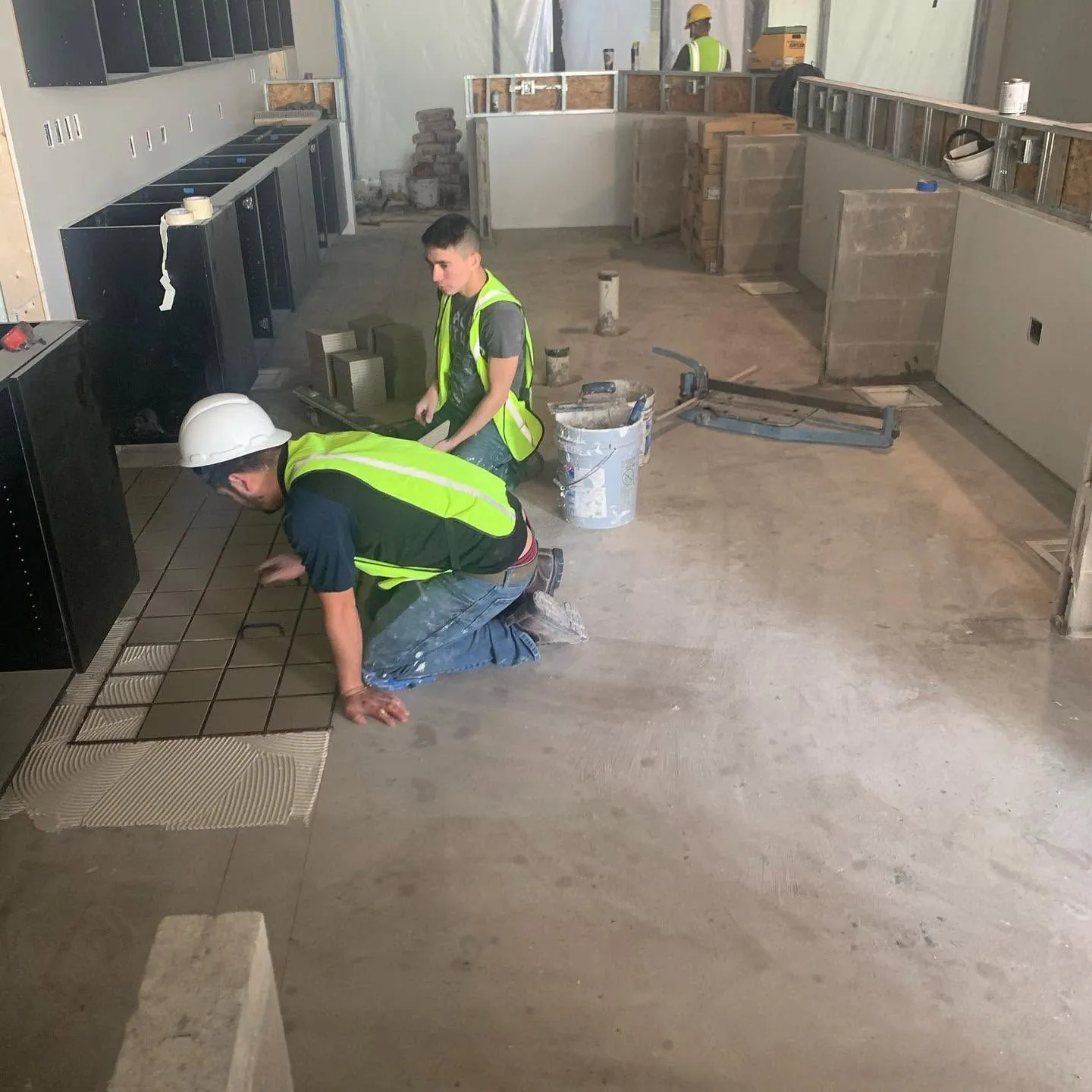 Crew in safety vests installing flooring in an open interior